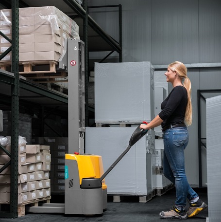 Une femme lève des palettes avec un chariot élévateur