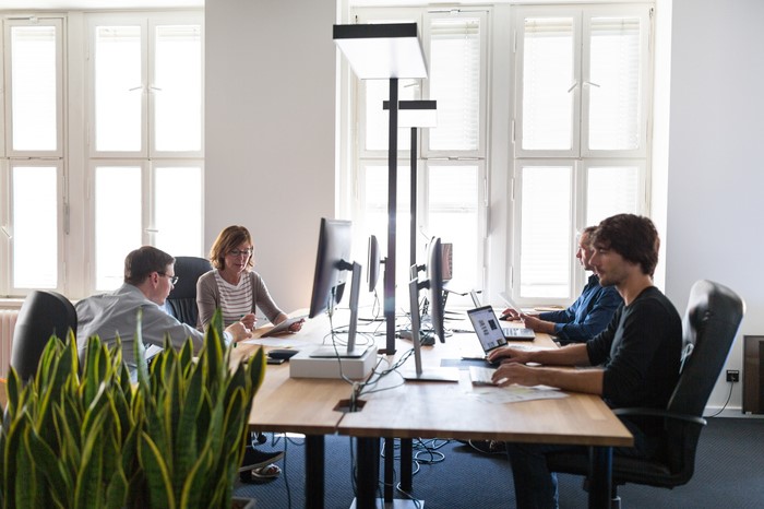 Menschen sitzen an beleuchteten Arbeitsplätzen im Büro