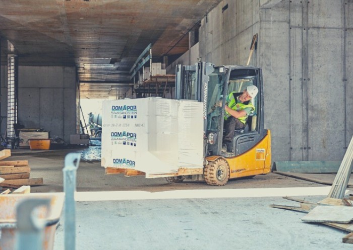 Ein Mann fährt einen beladenen Gabelstapler auf einer Baustelle