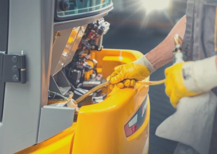 Eine Person füllt Hydrauliköl in einen Gabelstapler