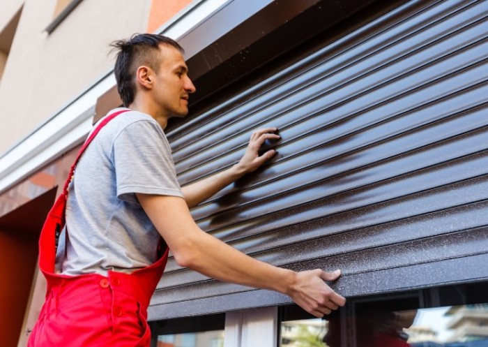 Mann arbeitet an Rollladen