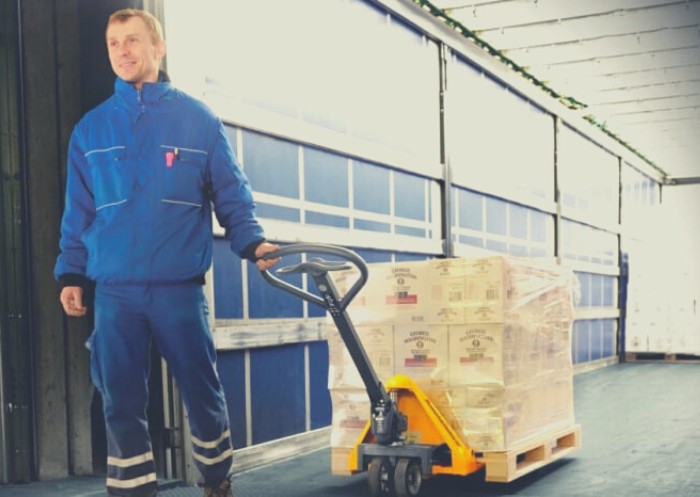Ein Mann zieht einen Hubwagen über die Ladefläche eines LKW