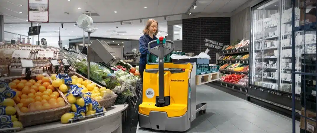 Eine Frau, die mit einem Hubwagen das Bestellrhythmusverfahren in einem Supermarkt umsetzt